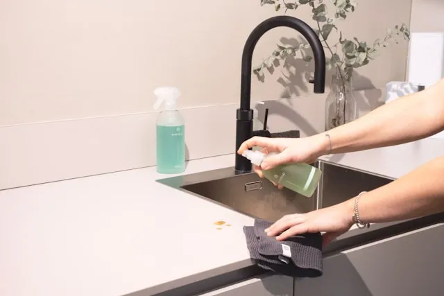 Hands cleaning dishes with natural dish soap in a kitchen sink